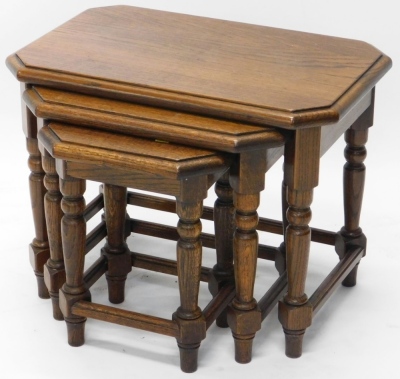 A nest of three oak tables, each with canted corners, on turned cylindrical legs, the largest 47cm high, 59cm wide, 39cm deep.