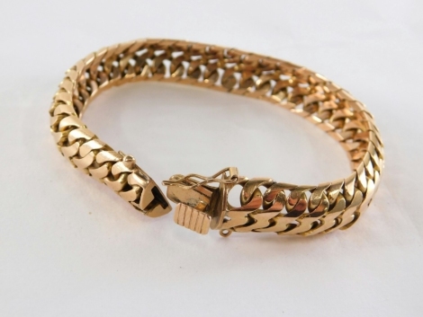 A curb link bracelet, of arch design, with clip clasp and safety clasp, yellow metal, stamped 18k, 20cm long, 56.3g all in. The links possibly filled.