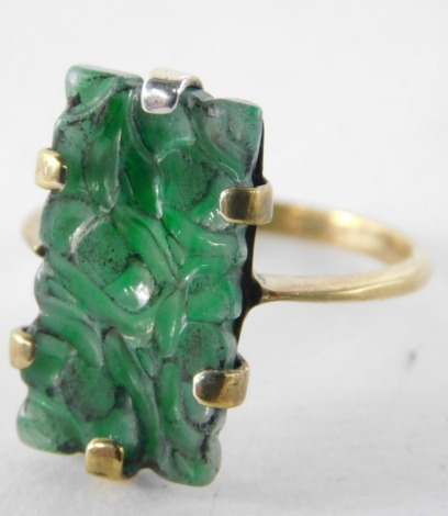 A carved jade dress ring, the rectangular carved jade panel in claw setting on a yellow metal band stamped 9K, 3.1g all in.