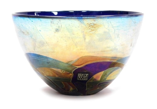 A Michael Harris Isle of Wight glass 'Nightscape' bowl, decorated with iridescent trails against a blue ground, with paper label and signed to underside, 15.5cm diameter, boxed.