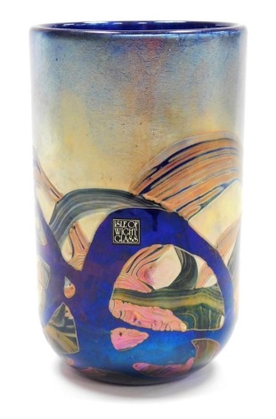 A Michael Harris Isle of Wight glass 'Nightscape' vase, of cylindrical form, decorated with iridescent trails against a blue ground, with paper label and signed to underside, 15.5cm high, boxed.