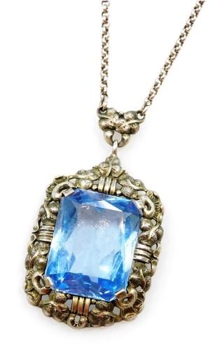 A silver and blue stone set pendant, possibly an aquamarine, rectangular facet cut, in a foliate pendant mount, on a curb link neck chain, the stone approx 16¾ct.