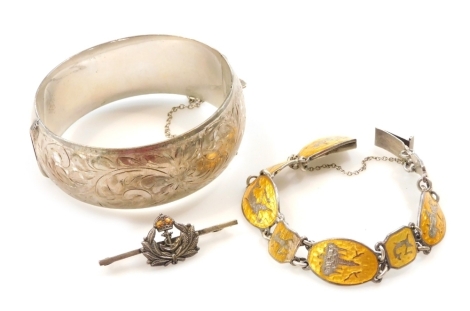 A silver bangle, floral and foliate engraved, on a snap clasp, with safety chain as fitted, Siam silver and yellow enamel bracelet, the oval and octagonal links niello decorated with temples and figures, on a snap clasp, and a Royal Naval silver and ename