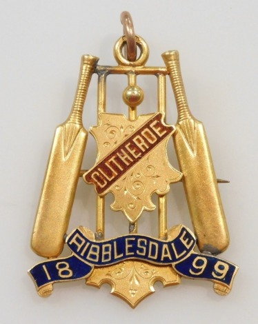 A 9ct gold and enamel cricketing medallion, with loop suspension, formed as the stumps, cricket ball and a pair of cricket bats, centered by a shield engraved and named Clitheroe, above a banner named Ribblesdale 1899, 11.2g.