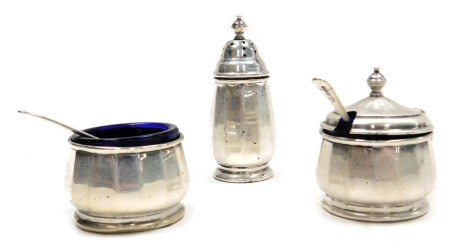 An Elizabeth II silver three piece cruet, comprising pepper pot, open salt with blue glass liner, mustard pot with blue glass liner, Birmingham 1960 and 1961, together with an associated salt and mustard spoon, weighable silver 2.36oz.