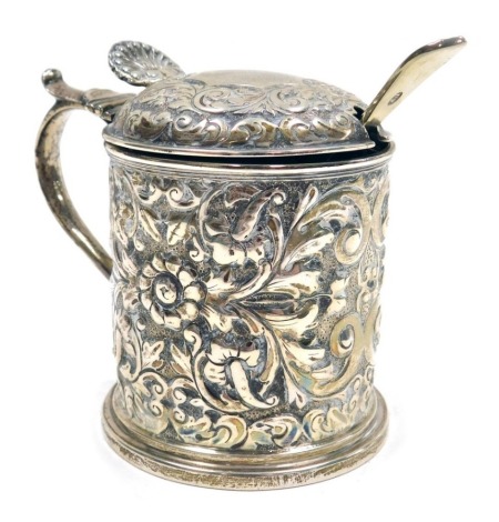 A Victorian silver mustard pot, the body and lid embossed with flowers, leaves and scrolls with a shell shaped thumb press, blue glass liner, Horace Woodward & Co (Edgar Finley & Hugh Taylor), London 1891, 7cm high, together with a silver plated mustard s