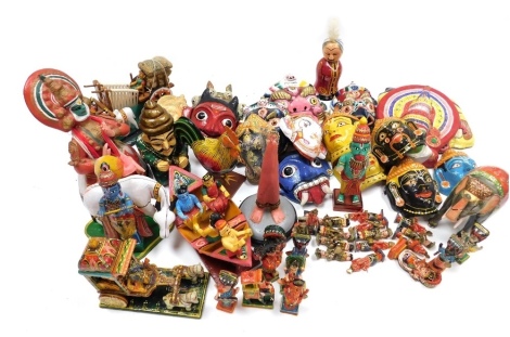 A group of Indian papier mache wall masks, to include depictions of demons, miniature papier mache figures in military dress, elephants playing musical instruments, carved treen figures depicting deities in a boat, painted elephant, etc. (3 tray)