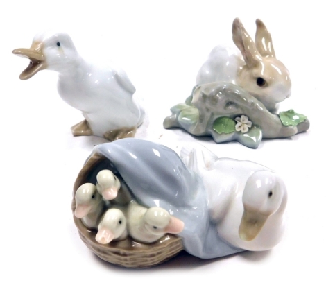 A Lladro porcelain figure of a rabbit beside a tree branch, printed marks, 10cm wide, together with a Lladro figure group of a goose and ducklings, 10cm wide, and a further Nao figure of a duck, 8cm high.