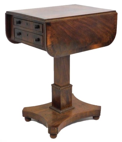 A Regency mahogany and rosewood cross banded drop leaf work table, with two frieze drawers raised on a square column, above a quatrefoil base, raised on bun feet, 70cm high, 53cm wide, 39cm deep, 74cm extended.