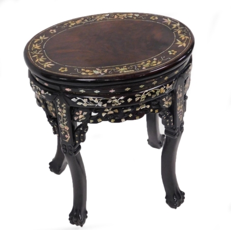 An Indian hardwood and mother of pearl inlaid occasional table, the oval top decorated with an outer border of mother of pearl flowers and leaves, raised on carved ball and claw feet united by pierced floral aprons, 52cm high.