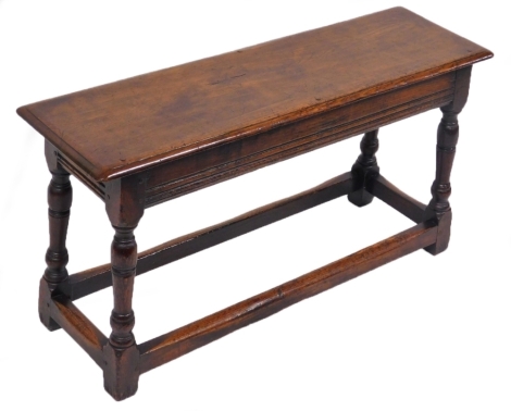 An 18thC style oak stool, the top with a moulded edge above four turned legs, united by stretchers, 48cm high, 92cm wide, 28cm deep. AUCTIONEER ANNOUNCE - Change to original description