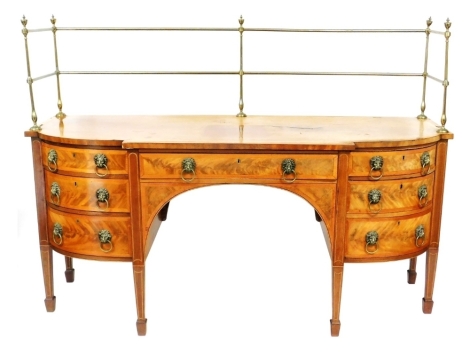 A George III flame mahogany break front sideboard, with brass curtain rail to the top and curved cross banded borders, with centre frieze drawer flanked by three curved and graduated drawers to each side, with brass lion's head ring handles, raised on squ