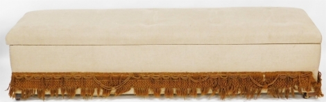 A mid 20thC ottoman, upholstered in fawn coloured fabric, with tassel fringe, on castors, 49cm high, 207cm wide.