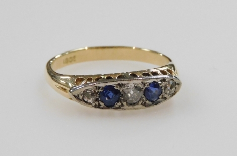 A diamond and sapphire five stone ring, in an oval channelled claw setting, in yellow metal, indistinctly stamped, diamonds approx ¾ct, size Q, 3.9g.