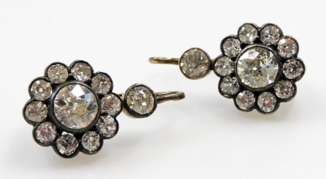 A pair of Victorian diamond drop earrings, of floral form, set in white and yellow metal, with fish hook backs, the central rose cut diamond in a surround of ten further diamonds, with a diamond above, each central diamond approx ¾ct, remaining diamonds a