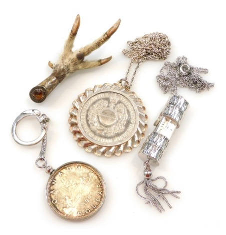 A Queen Elizabeth II Silver Jubilee commemorative coin, in a silver mount on chain, Canada 1966 dollar, in a key fob mount, Scottish silver mounted bird claw brooch, and a Gradus pendant watch, on a plated chain. (4)