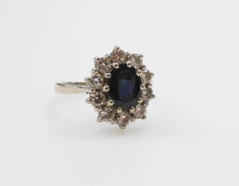 An 18ct white gold sapphire and diamond ring, the oval cut sapphire in a surround of diamonds, diamonds approx &#8532?ct, size L/M, 5.2g.