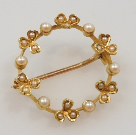 A circular seed pearl set brooch, in a berry and clover leaf alternating design, set in yellow metal, 3.0g.