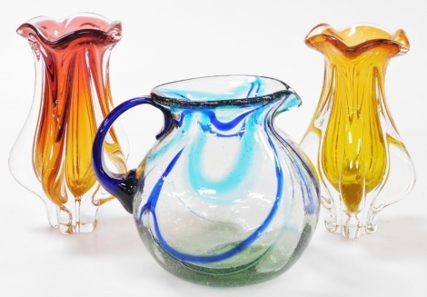 Three items of coloured glass wares, comprising a Chribska glass vase of shaped baluster form, in graduated pink to orange colourway, 24cm high, another similar, together with a glass jug of globular form decorated with flashes of dark and pale blue, 19cm