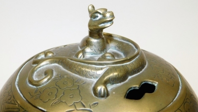 A Qing Dynasty Chinese bronze censer and cover, embossed with reserves of figures in a garden, the lid with a dragon finial, raised on three cabriole legs, with a hardwood stand, 23cm high. - 3