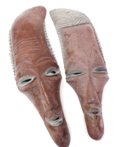 A pair of African tribal masks, of elongated mannerist form, 80cm and 75cm high.