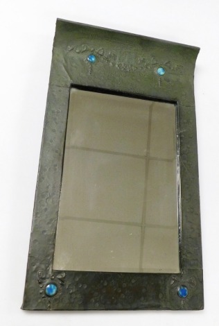 An Arts & Crafts hammered pewter wall mirror, of rectangular form, with a slopped top, decorated with bows inset with Ruskin type blue coloured enamel roundels, 70cm x 40cm.