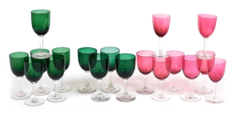 A group of Edwardian coloured wine glasses, comprising eight cranberry and ten green glasses. (18)