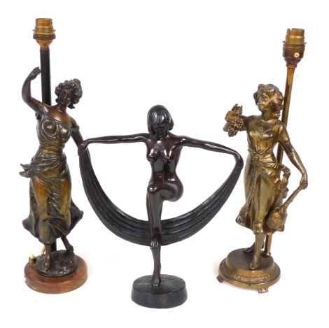 An early 20thC spelter figure of a nude dancing woman, 29cm wide, and a near pair of cold painted spelter figural table lamps, 39cm high. (3)