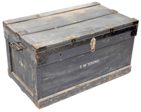 An early 20thC painted pine travelling trunk, with metal mounts with two rings and handles to each side, stamped to the front F.M.Young, on a plinth base, 49cm high, 94cm wide, 54cm deep.