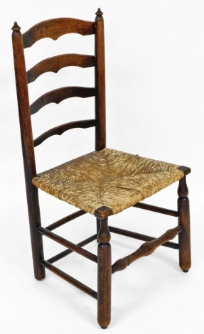 A 19thC oak ladder back chair, with rush seat, raised on cylindrical turned legs united by stretchers.