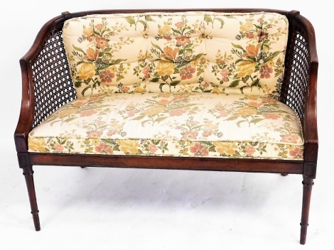 A Victorian mahogany framed bergere sofa, with caned curved back, with floral upholstered seat and back cushion, raised on turned tapering legs, 76cm high, 113cm wide.