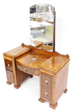 A mid century burr walnut dressing table, the mirror back above a central drawer flanked by two pairs of drawers, each with a marbled Bakelite drop handle, on block feet, 160cm high, 113cm wide, 54cm deep.