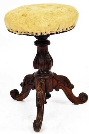 A Victorian mahogany revolving piano stool, with an overstuffed seat, raised on a turned and fluted column over three carved cabriole legs.