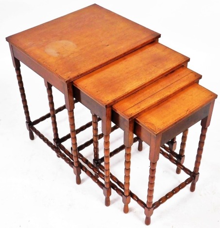 An early 20thC mahogany quartetto of occasional tables, raised on bobbin turned legs, united by bobbin turned stretchers, largest table 56cm high, 46.5cm wide, 40.5cm deep.