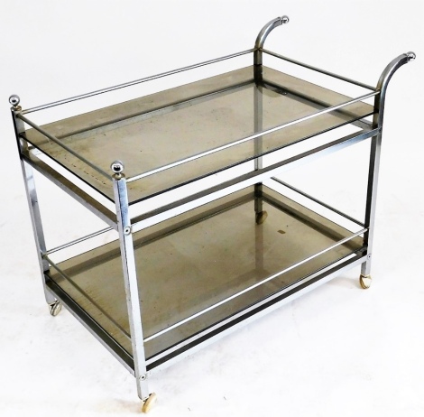 A vintage 1970s chrome and glass drinks cart, with a galleried top, raised on straight and curved supports united by a galleried under tier, on castors, 64cm high, 86cm wide, 48cm deep.