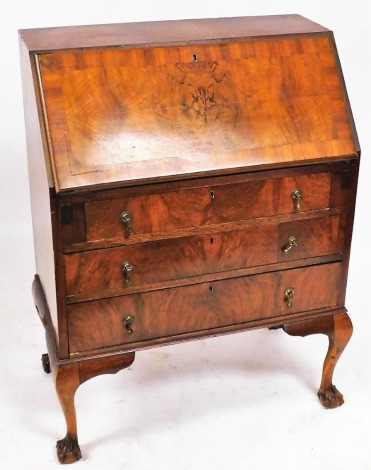 An early 20thC walnut and mahogany banded bureau, the fall flap opening to reveal two small drawers and six recesses, over one short and two long drawers, raised on cabriole legs on ball and claw feet, 100cm high, 77cm wide, 43cm deep.