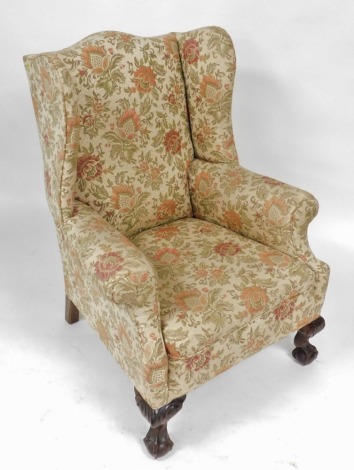 An early 20thC mahogany wingback armchair, upholstered in floral fabric, raised on carved cabriole legs, on ball and claw feet, 80cm wide.