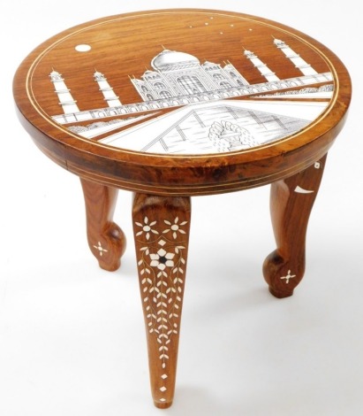 An Indian Sheesham wood and bone inlaid occasional table, the circular top decorated with Taj Mahal, raised on three elephant's head legs, 30cm high, 30cm wide.