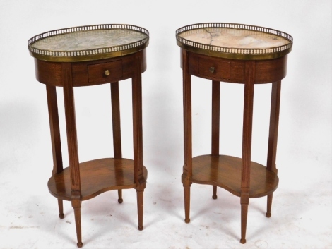 A pair of French Louis XVI style oval mahogany side tables, with galleried marble tops, over a single small frieze drawer, raised on fluted and turned legs, united by a kidney shaped under tier, 75cm high, 41.5cm wide, 30cm deep.