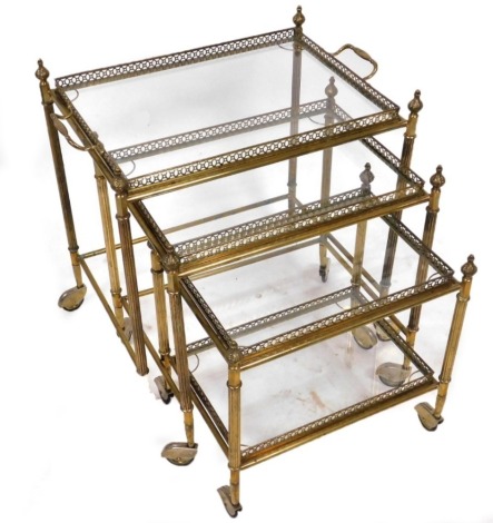 A late 20thC brass nest of drinks trolleys, the largest trolley with a twin handled tray top, the others with glass bottom trays, raised on castors, largest trolley 61cm high, 58cm wide, 45cm deep.