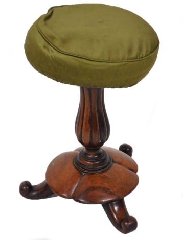 A Victorian rosewood revolving piano stool, raised on a fluted column over a circular base and scroll feet, 52cm high.