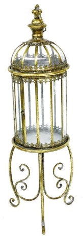 A Victorian style brass floor standing candle lantern, raised on three scrolling legs, 108cm high.