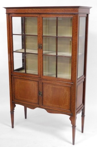 An Edwardian mahogany and line inlaid display cabinet, the out swept pediment over a pair of astragal glazed doors, inset bevelled glass, enclosing two shelves, above a pair of cupboard doors, raised on tapering square legs, 174cm high, 107cm wide, 44cm d