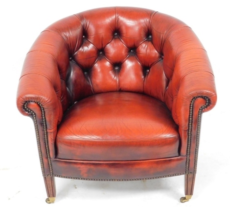 A mahogany and ox blood red leather button back armchair, raised on channelled square legs, on castors, 77cm wide.