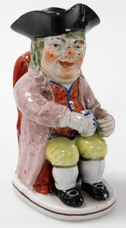 A 19thC Staffordshire Toby jug, of a seated figures holding a blue and white jug, 20cm high.