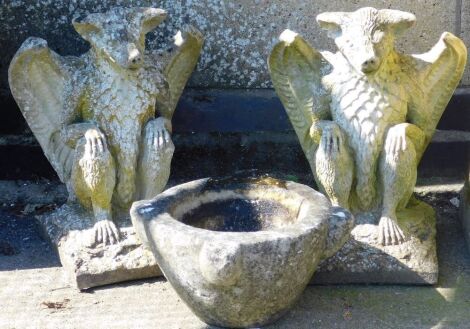 A pair of composition garden sculptures, modelled as griffins, on square bases, each 41cm high, together with a carved stone mortar, 30cm wide.