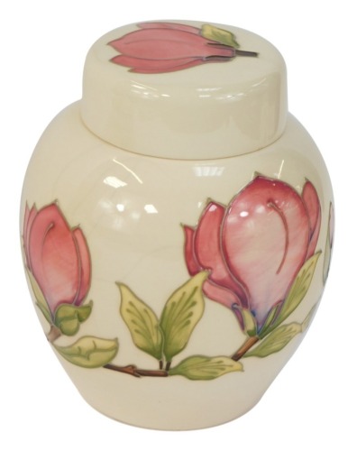 A Moorcroft Magnolia pattern ivory ground jar and cover, with green Moorcroft stamp and WM to underside, 21cm high.