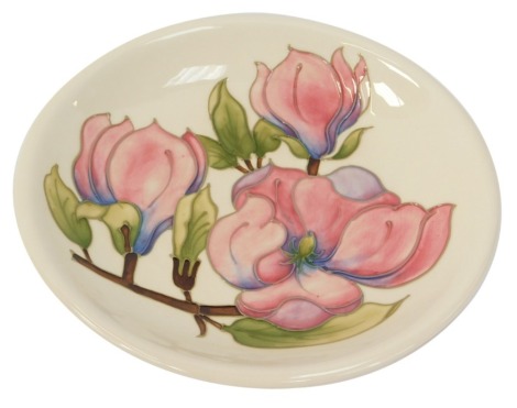 A Moorcroft Magnolia pattern ivory ground plate, stamped in green Moorcroft and signed WM, 26cm diameter.