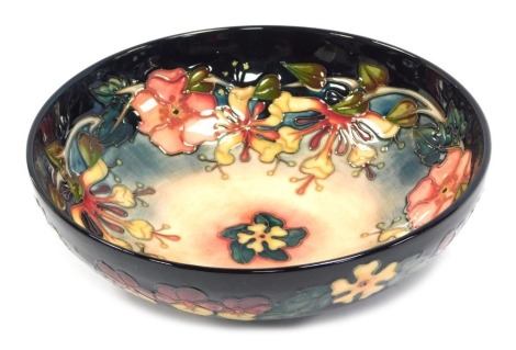 A Moorcroft pottery fruit bowl decorated in the Honeysuckle pattern, impressed and painted marks, 26cm diameter.