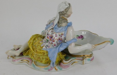 A 19thC Meissen porcelain figural sweetmeat dish, modelled as a partially clad lady holding a large scalloped bowl, polychrome decorated with rococo base, crossed swords mark in blue, 32cm wide. (AF, restored and repaired) - 2